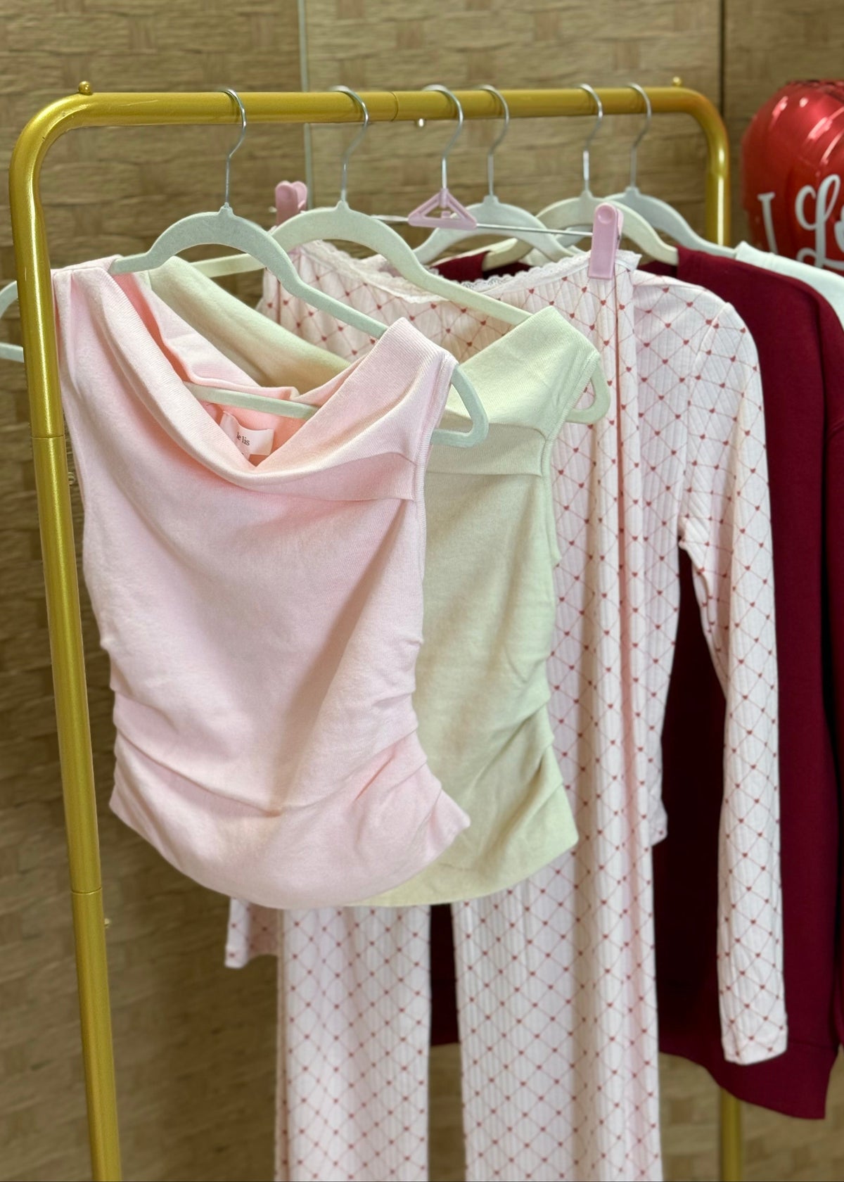 Clothing items on hangers against a beige wall with balloons in the background.