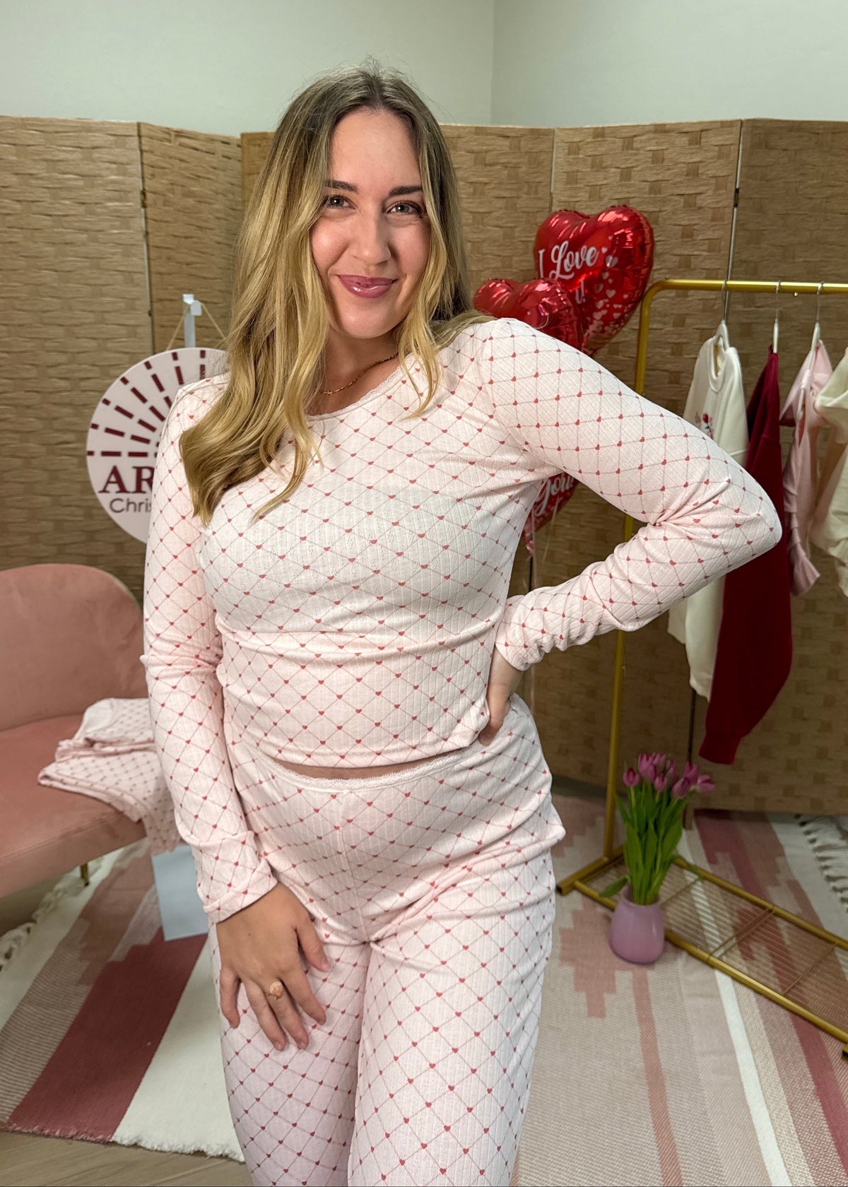 Woman in a heart pattern pajama set posing in a room with decorative elements.