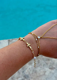 Gold bracelets on a wrist with a blue water background