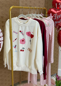 White sweatshirt with heart and balloon designs on a rack with balloons in the background
