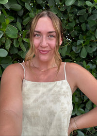 Woman in a white dress standing among green bushes